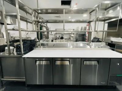 Stainless steel preparation bench and overhead shelving in the kitchen