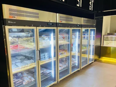 Upright glass door display freezers stocked at NAK Meats