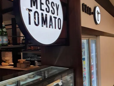 Illuminated signage above the refrigerated display at The Messy Tomato